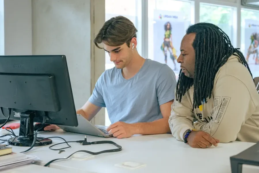 Two colleagues collaborating on laptop project in office for Social Impact Consulting