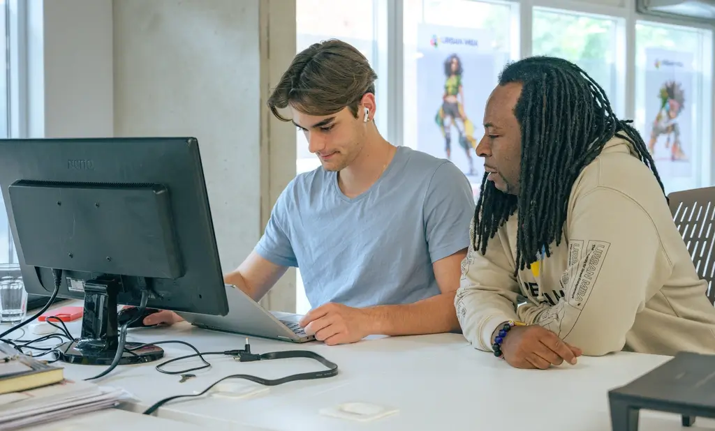 Two colleagues collaborating on laptop project in office for Social Impact Consulting